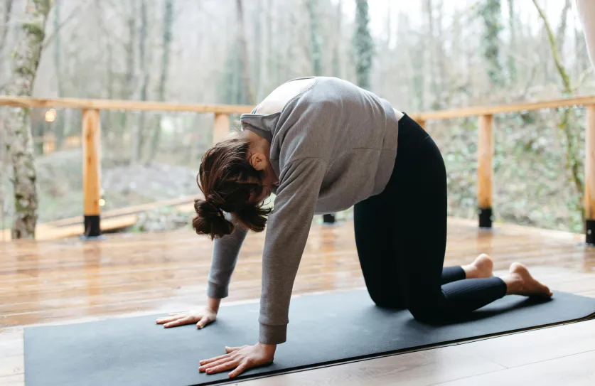Vrouw die kat koe yogaoefeningen doet